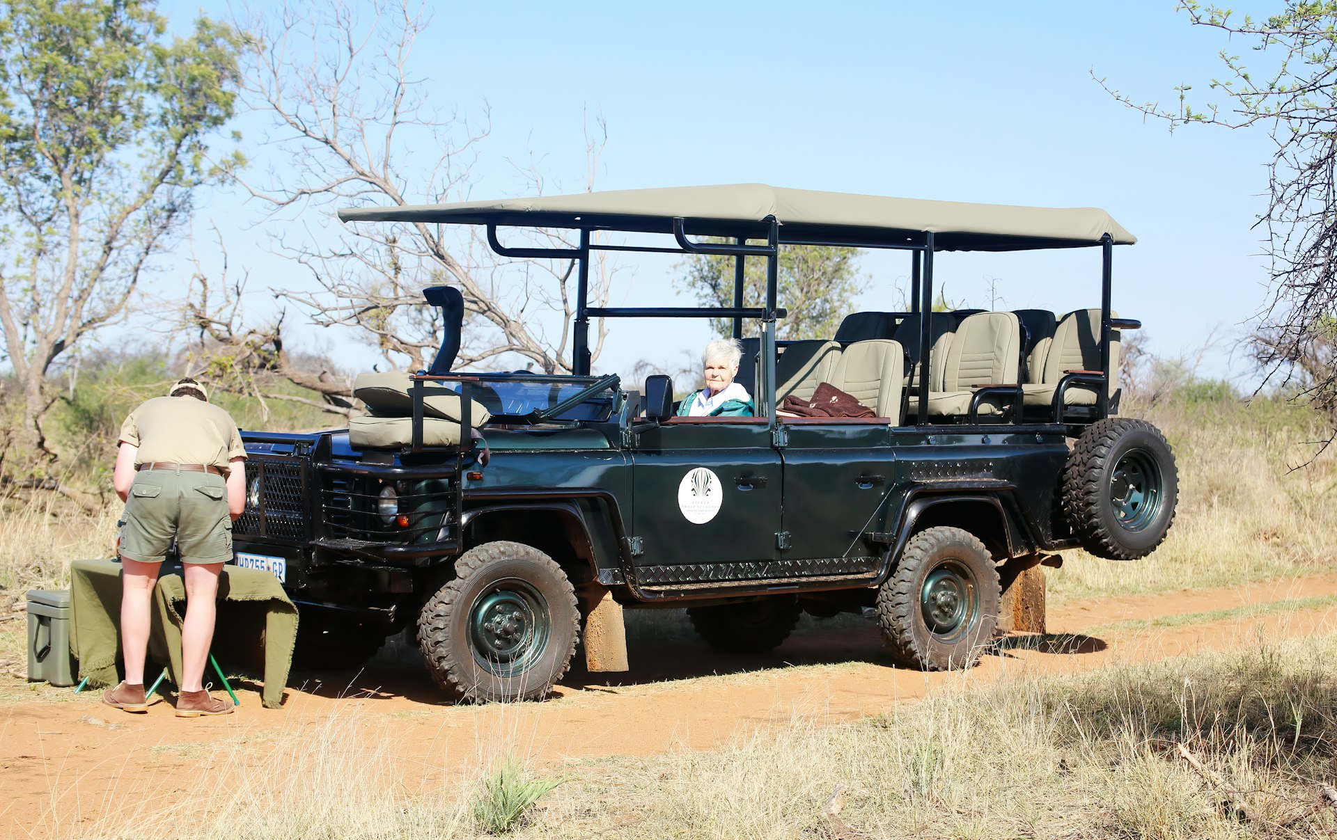 a man standing next to a black jeep on a dirt road